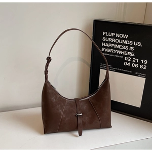 Detail of dark brown suede crescent shoulder bag with silver buckle and matte finish