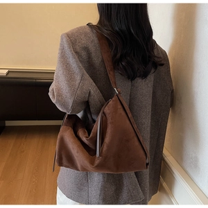 Detail of dark brown suede hobo bag showing large capacity and soft drape on model