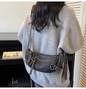 Detail of dark grey washed denim crossbody bag with metal zippers and cargo style straps