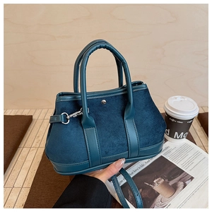 Detail view of navy blue suede handbag with metal rivets and stylish leather stitching