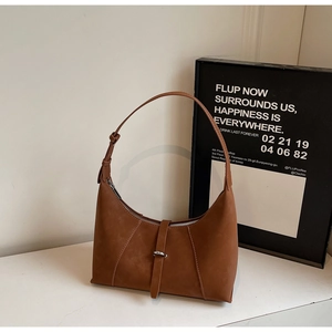 Macro detail of brown suede crescent bag with decorative stitching and metal buckle