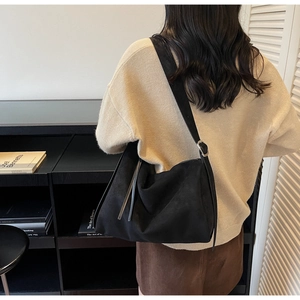 Detail view of black frosted leather tote bag with long tassel and adjustable silver buckle