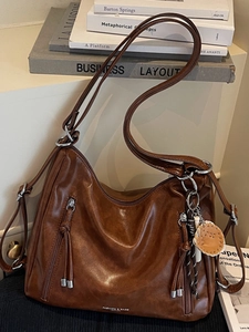 Retro brown leather crescent tote bag with fringe zippers and baseball glove charm