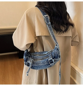 Close-up of washed denim shoulder bag with white Fashion embroidery and metal eyelets