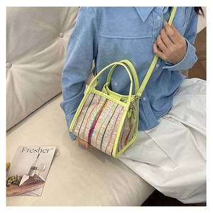Détail d'un sac cabas tissé beige aux rayures colorées et finitions en cuir vert fluo