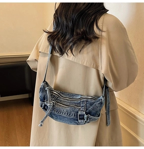 Detail view of washed blue denim crescent bag with fashion embroidery and metal zippers