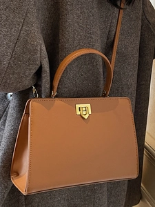 Sac cabas classique en cuir marron avec boucle dorée porté par un mannequin en manteau