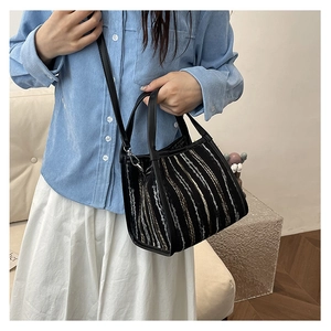 Détail d'un sac bandoulière en tweed rayé avec garniture en cuir noir et bandoulière