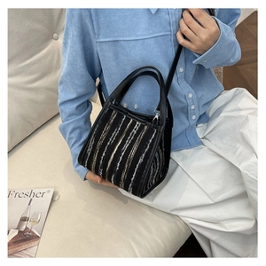 Détail d'un sac seau en tweed rayé avec poignées en cuir et une fine bandoulière élégante