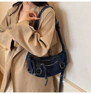Detail of blue denim crossbody bag with Fashion logo and adjustable shoulder strap