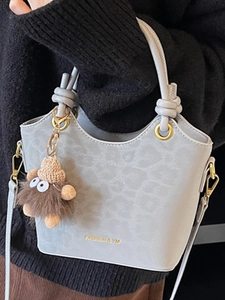 Light blue leopard print bucket bag with plush monster charm and golden hardware detail