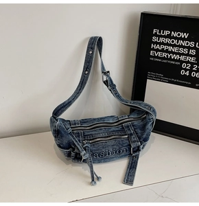 Detail of dark blue denim tote bag featuring dual front zippers and fashion embroidery
