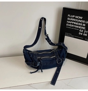 Detail of blue denim tote bag with metal zippers and adjustable eyelet strap