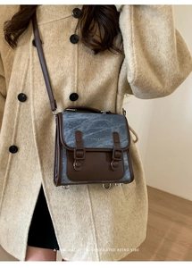 Dettaglio che mostra il contrasto tra denim blu e pelle marrone su questo zaino vintage