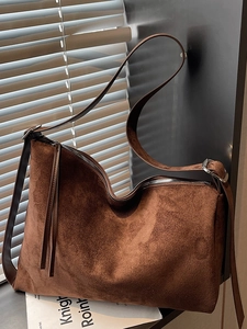 Dark brown suede hobo bag with adjustable strap shown in aesthetic natural light