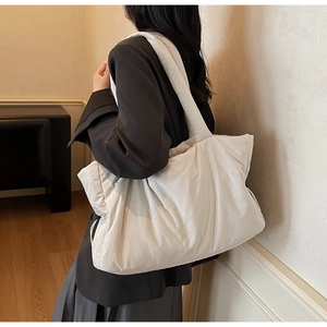 Close-up of a white padded tote bag with quilted texture shown on model for daily commute