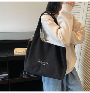 Dettaglio della borsa tote in velluto a coste nero con ricamo indossata da una modella
