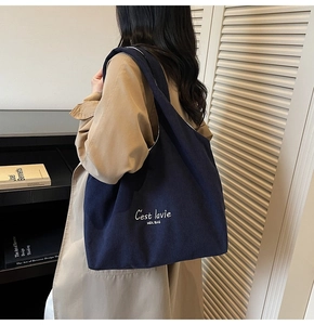 Dettaglio della borsa tote in velluto a coste blu scuro con ricamo bianco e stile urbano