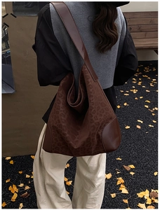 Detail view of large leopard print tote bag on shoulder with autumn leaf background