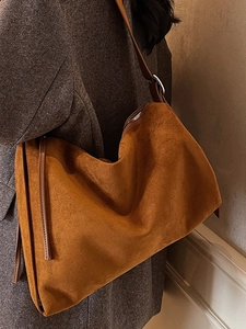 Caramel brown suede tote bag with adjustable shoulder strap shown on a model