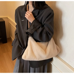 Dettaglio borsa tote in ecopelliccia color crema con elegante tracolla in pelle marrone