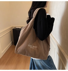 Dettaglio di una grande borsa tote in velluto marrone con stampa bianca sul modello
