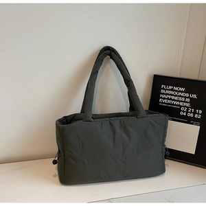 Detail of dark grey quilted puffer tote bag featuring soft padded handles and drawstring