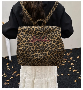 Close-up of leopard print backpack featuring red embroidery and golden hardware buckle