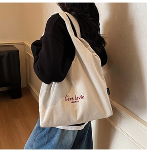 Dettaglio della borsa tote in velluto beige con ricamo rosso e trama a coste morbide