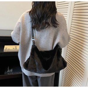 Dettaglio borsa hobo in ecopelliccia nera con sottile tracolla in pelle e anelli