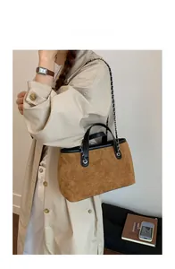 Brown suede tote bag side view with black leather handles and silver chain on model