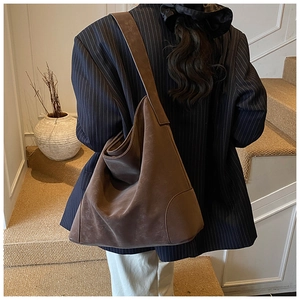 Detail of deep brown frosted leather tote bag showing shoulder strap and side stitching