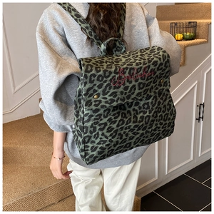 Detail of green leopard print backpack with red embroidered logo on a stylish model