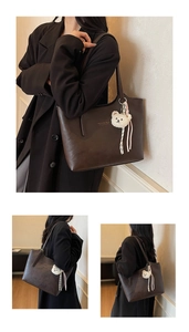 Close-up of a brown leather tote bag with a cute bear plush charm and striped ribbon detail