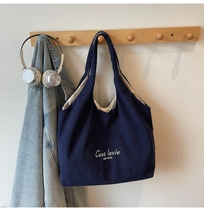 Dettaglio borsa tote in velluto a coste blu scuro con ricamo bianco su gancio
