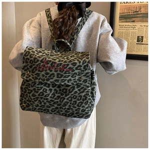 Detail showing vintage leopard print backpack with pink embroidery and metallic snap button