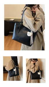 Detail view of black PU tote bag featuring a cute white plush bear and striped tassels