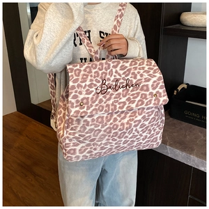 Detail of trendy leopard print backpack with flip-top cover and metal buckle accents