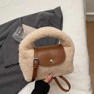 Détail du sac beige en peluche avec bandoulière en cuir marron et boucle métallique