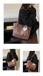 Detail of a brown leather tote bag with a white plush bear charm and gold buckle accents