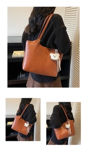 Detail view of brown large tote bag with cute bear charm and striped ribbon accessory