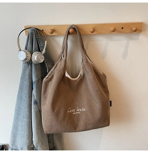Borsa tote in velluto a coste marrone con ricamo bianco appesa in una scena di vita quotidiana