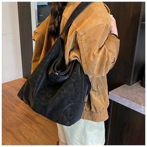 Detail of a large black suede tote bag showing its vintage texture and slouchy shape