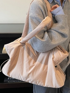 Pink quilted puffer tote bag with side drawstring detail worn over the shoulder