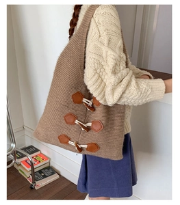 Détail d'un sac cabas en tricot marron avec fermoirs brandebourg porté par un mannequin