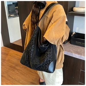 Detail view of large leopard print tote bag with matte texture on model's shoulder