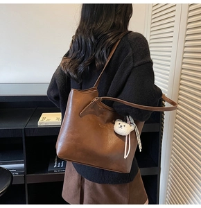 Detail view of coffee brown large tote bag with cute white teddy bear plush charm