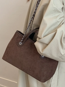 Minimalist coffee brown suede tote bag with silver chain strap shown on a female model