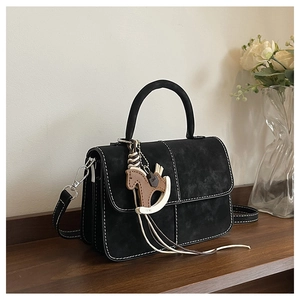 Detail of black textured handbag with contrast white stitching and decorative horse charm