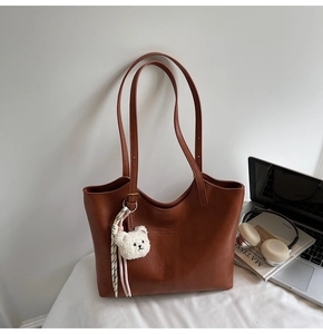Brown faux leather tote bag with plush bear charm and chic minimalist work accessories